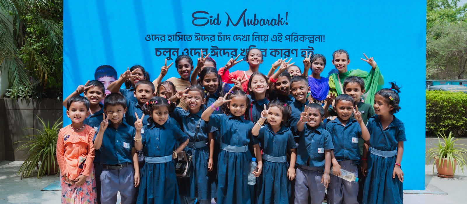 Children at a Youth Worldwide Foundation Eid event, in front of a backdrop carrying the Youth's Voice, Maya and Youth Worldwide Foundation logos